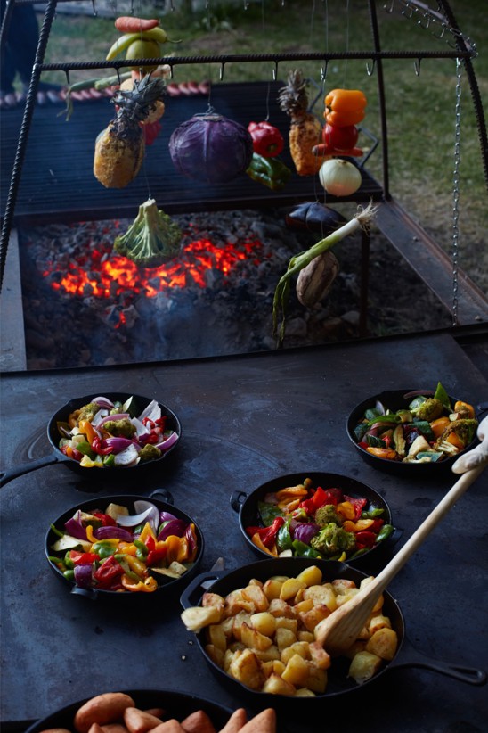 Vegetables and potatoes being on a large cast iron grill.